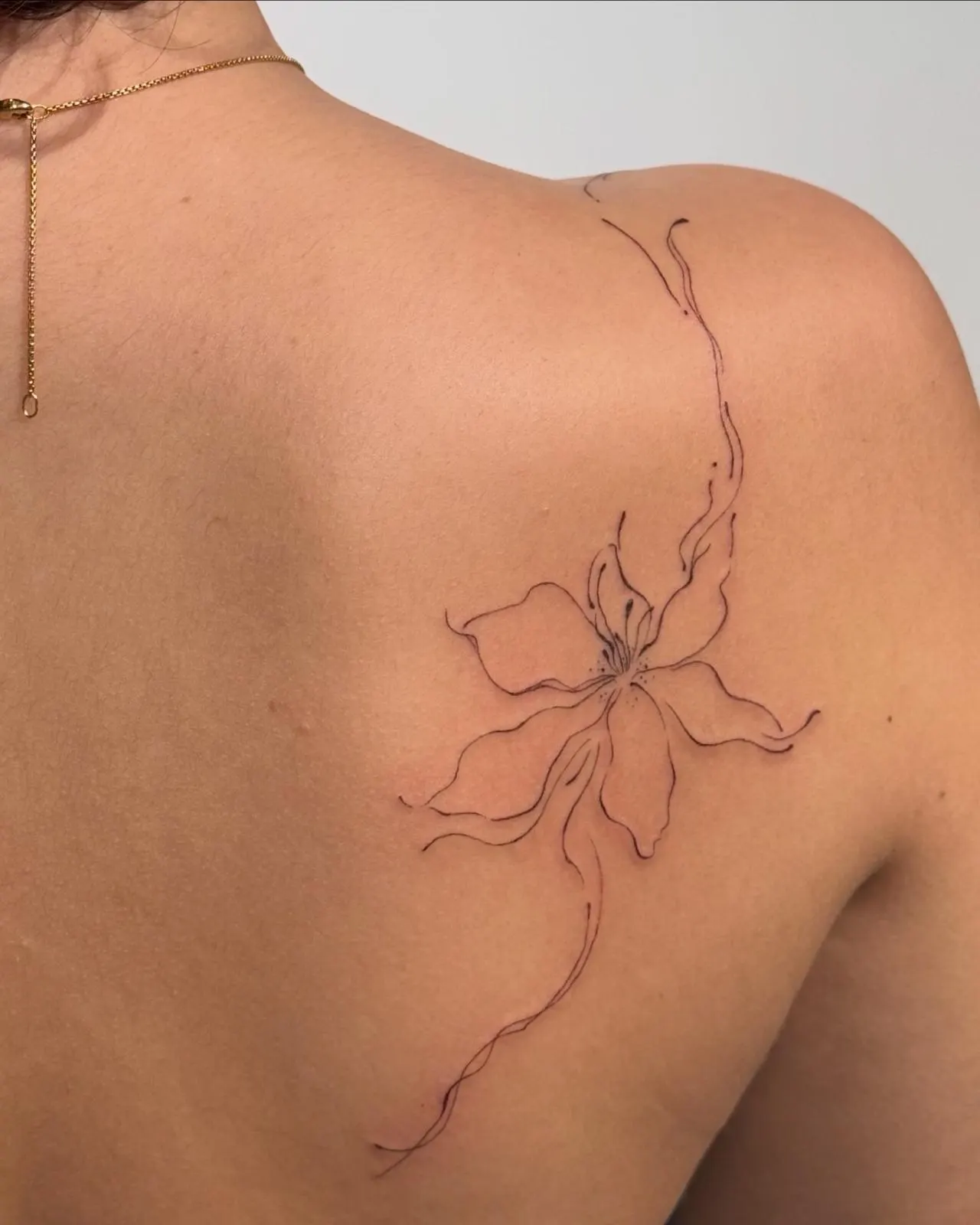 Lily fine line back shoulder blade tattoo