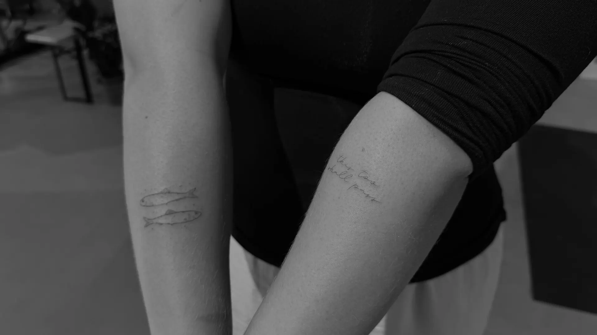 Mini Fische und Lettering Tattoos an den Armen schwarz-weiss